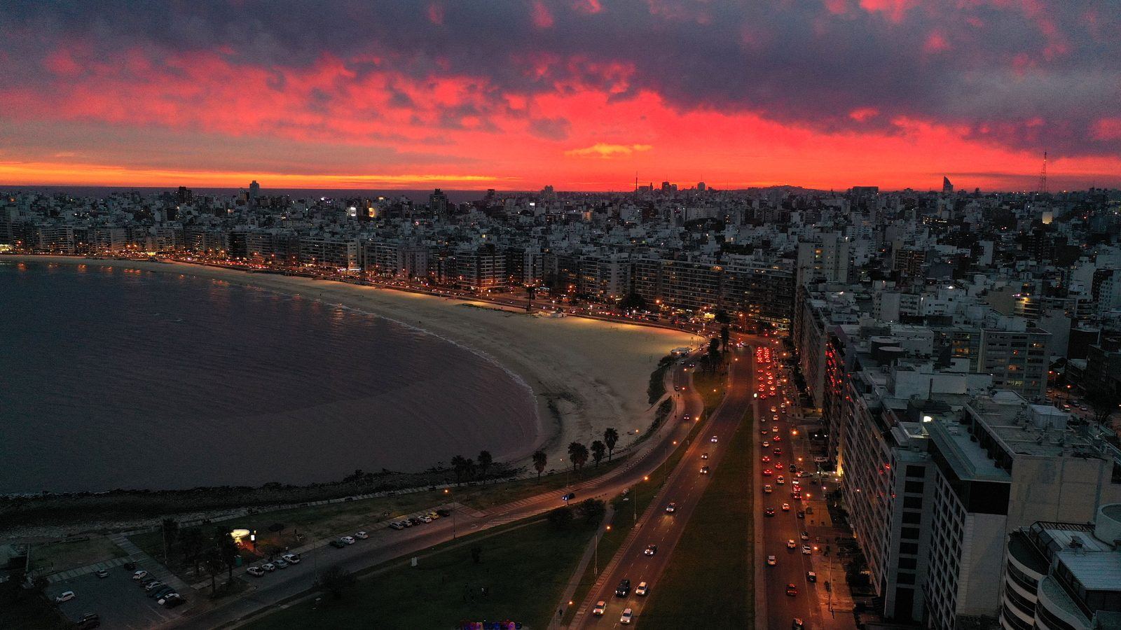 Vista aérea de la rambla y la playa de Pocitos, en Montevideo, al atardecer, con la línea de edificios frente al Río de la Plata.