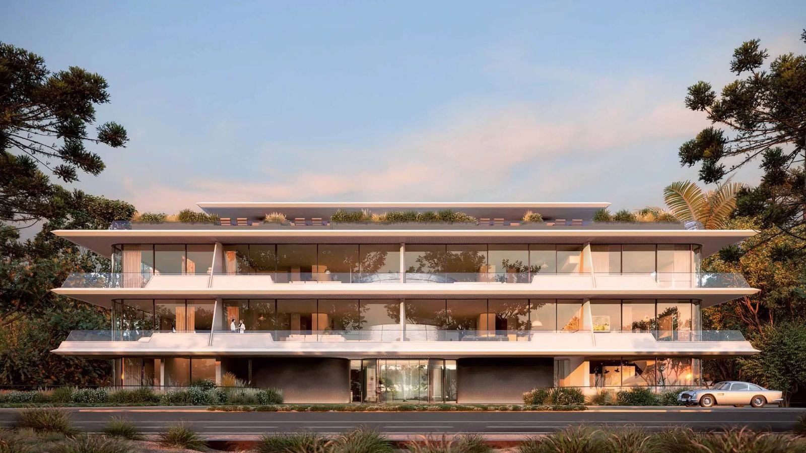 Rendering of The Edge's façade: a low-rise white-concrete residential building with planted terraces at sunset.